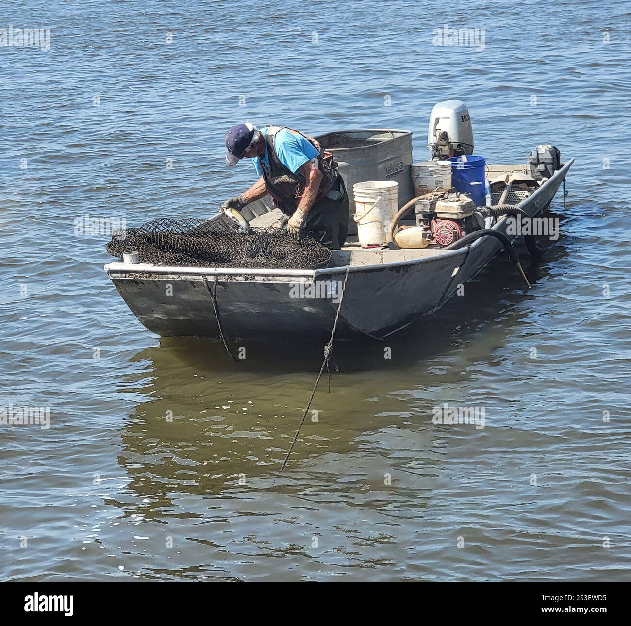 Elderly man fishing with a net on the Mississippi River at Muscatine, Iowa - Smartphone Captured Stock Image