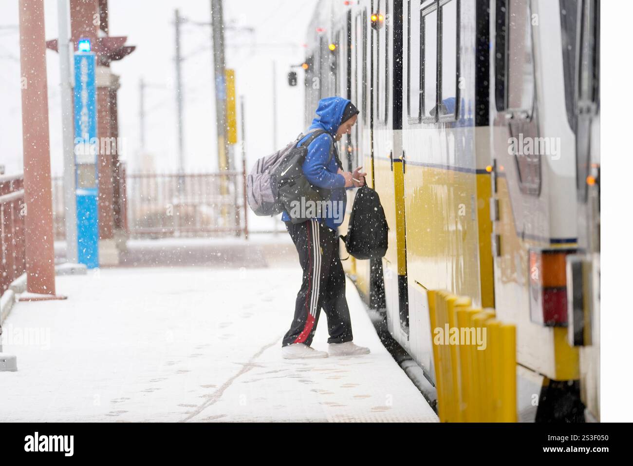 Snow falls as a person boards a DART train Thursday, Jan. 9, 2025, in