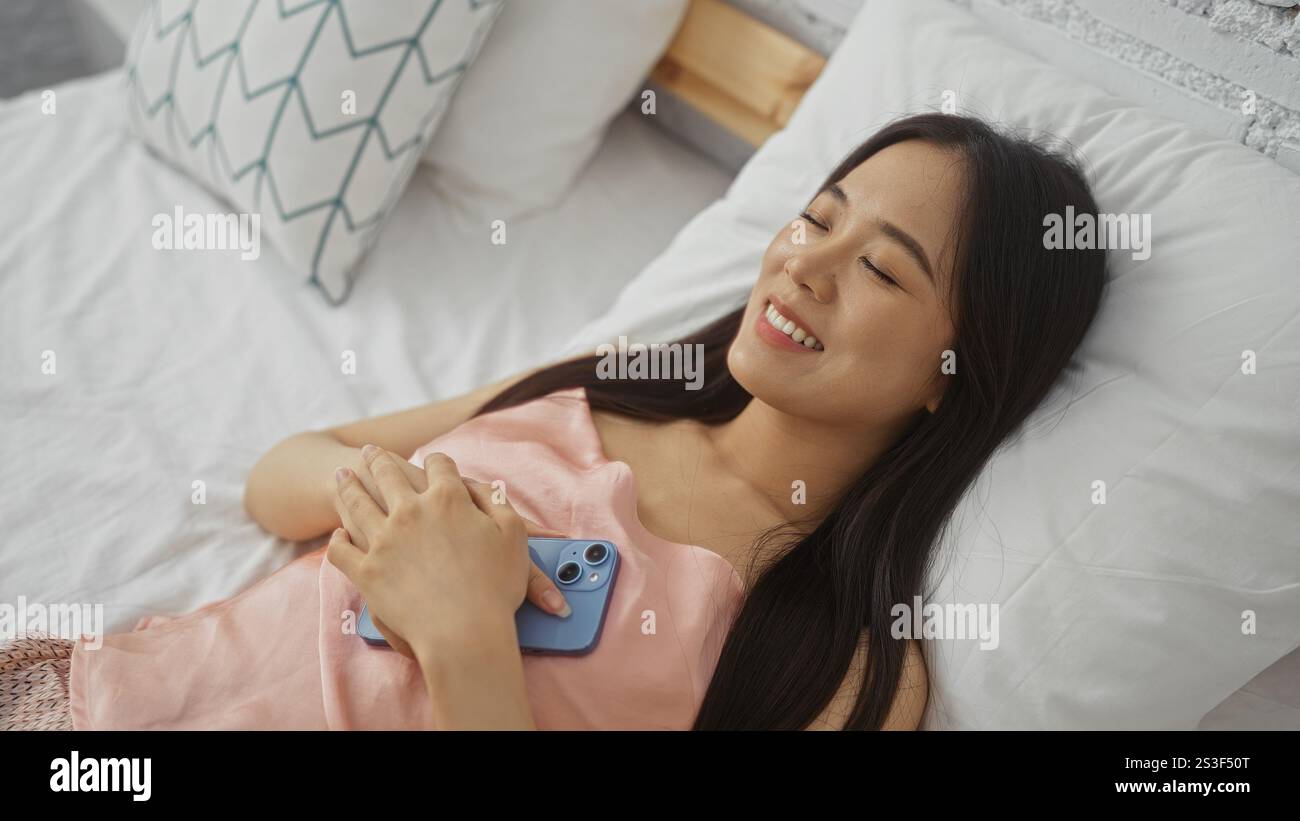 Young chinese woman lying on bed at home smiling peacefully while ...