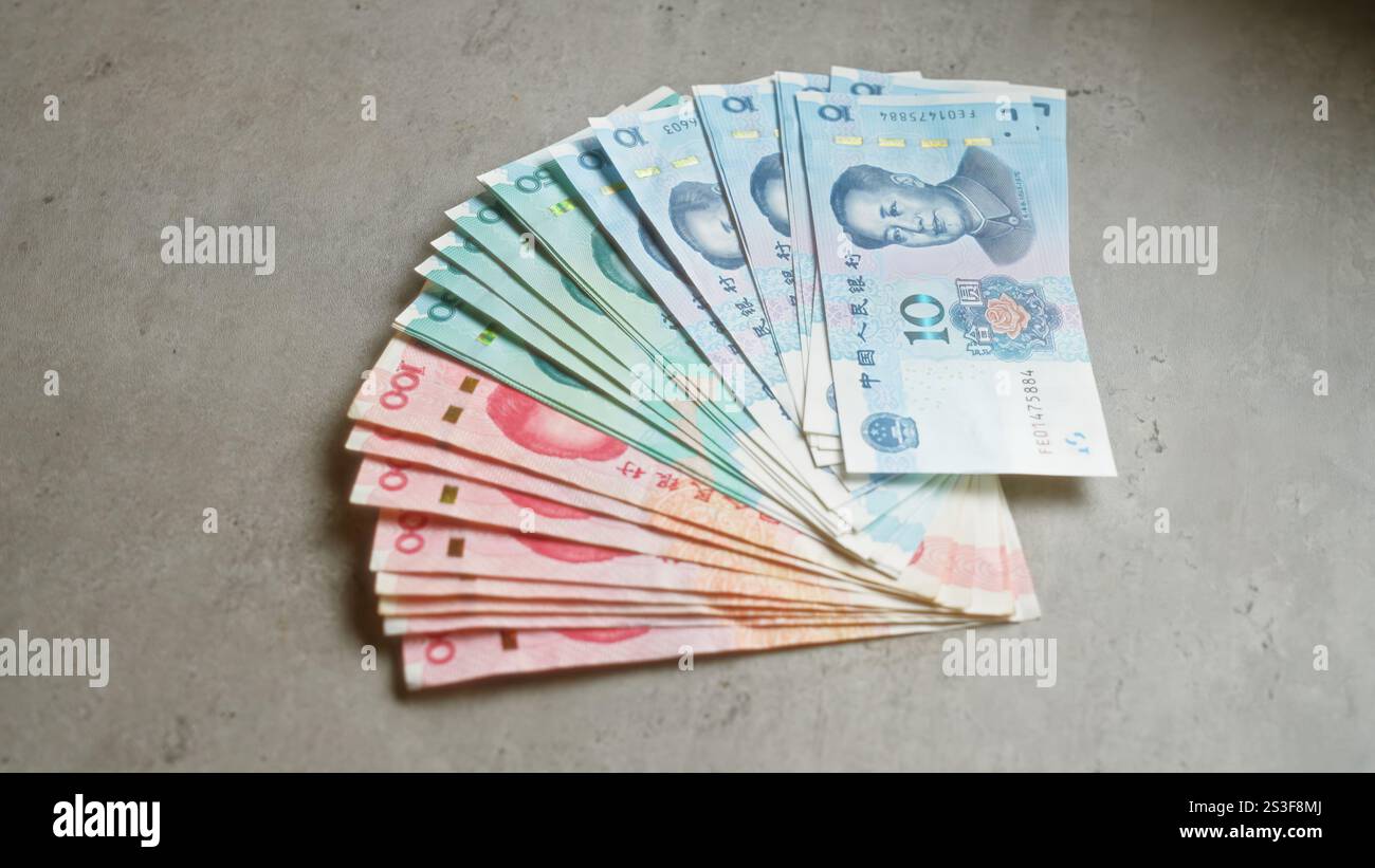 Chinese banknotes arranged in a fan shape on a concrete surface showcasing different denominations of yuan currency Stock Photo