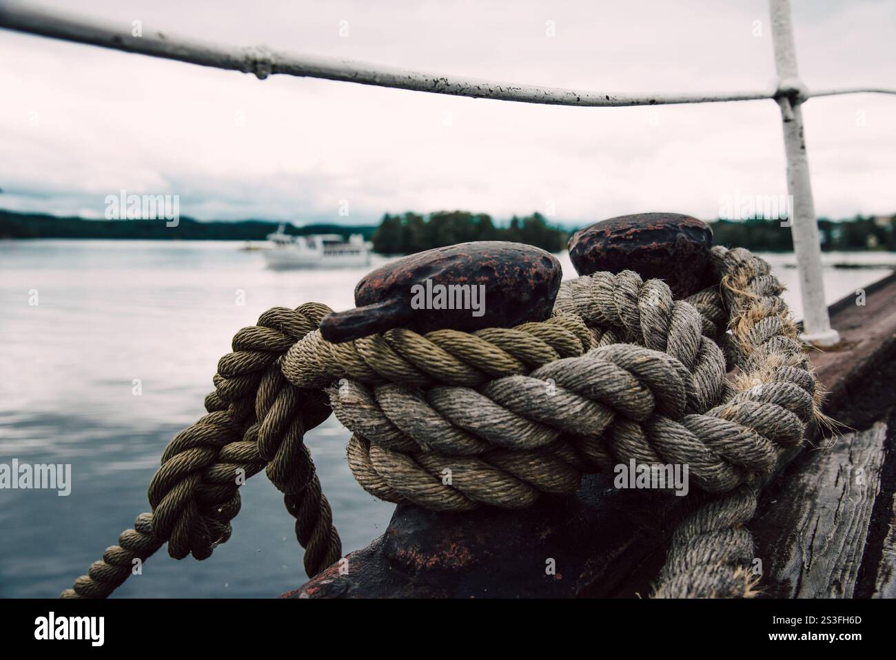 Large sea rope is tied to a metal holder at the river port of the ships ...