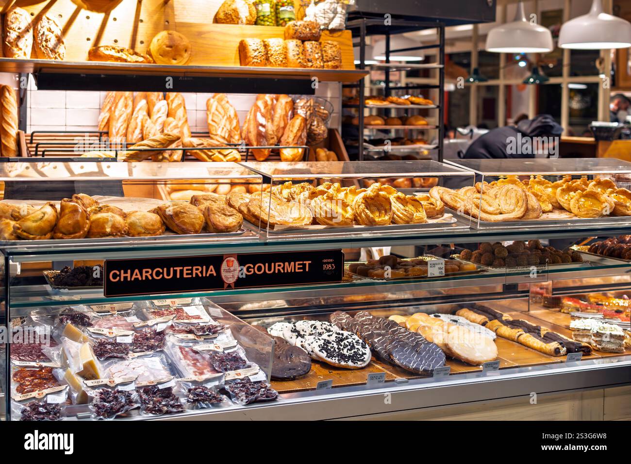 A display window case with bread, desserts, dried meats and pastries at a gourmet charcuteria and bakery in Seville, Spain. Stock Photo
