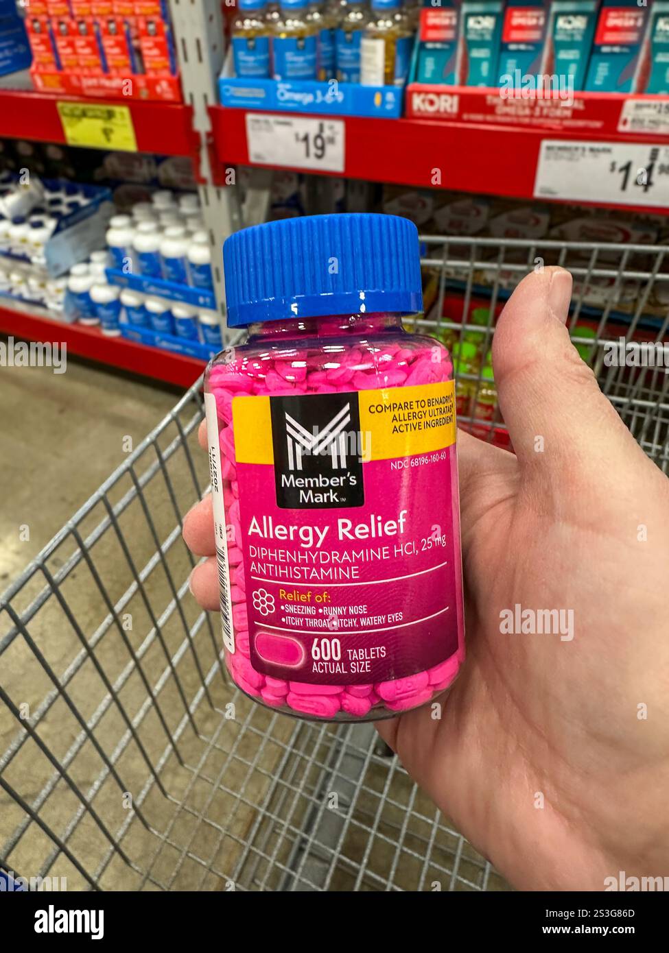 Bottle of Member's Mark Allergy Relief medication being held above a shopping cart - Smartphone Captured Stock Image