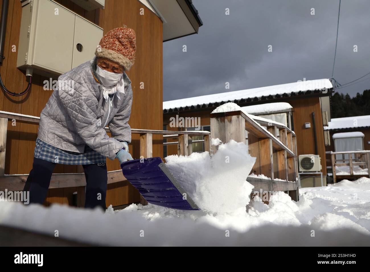 A woman removes snow at a temporary house area in Wajima City, Ishikawa