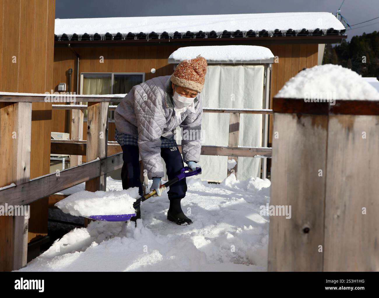 A woman removes snow at a temporary house area in Wajima City, Ishikawa