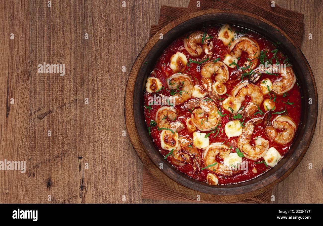 Saganaki with shrimp, in a clay pan, Greek dish, shrimp in tomato sauce ...