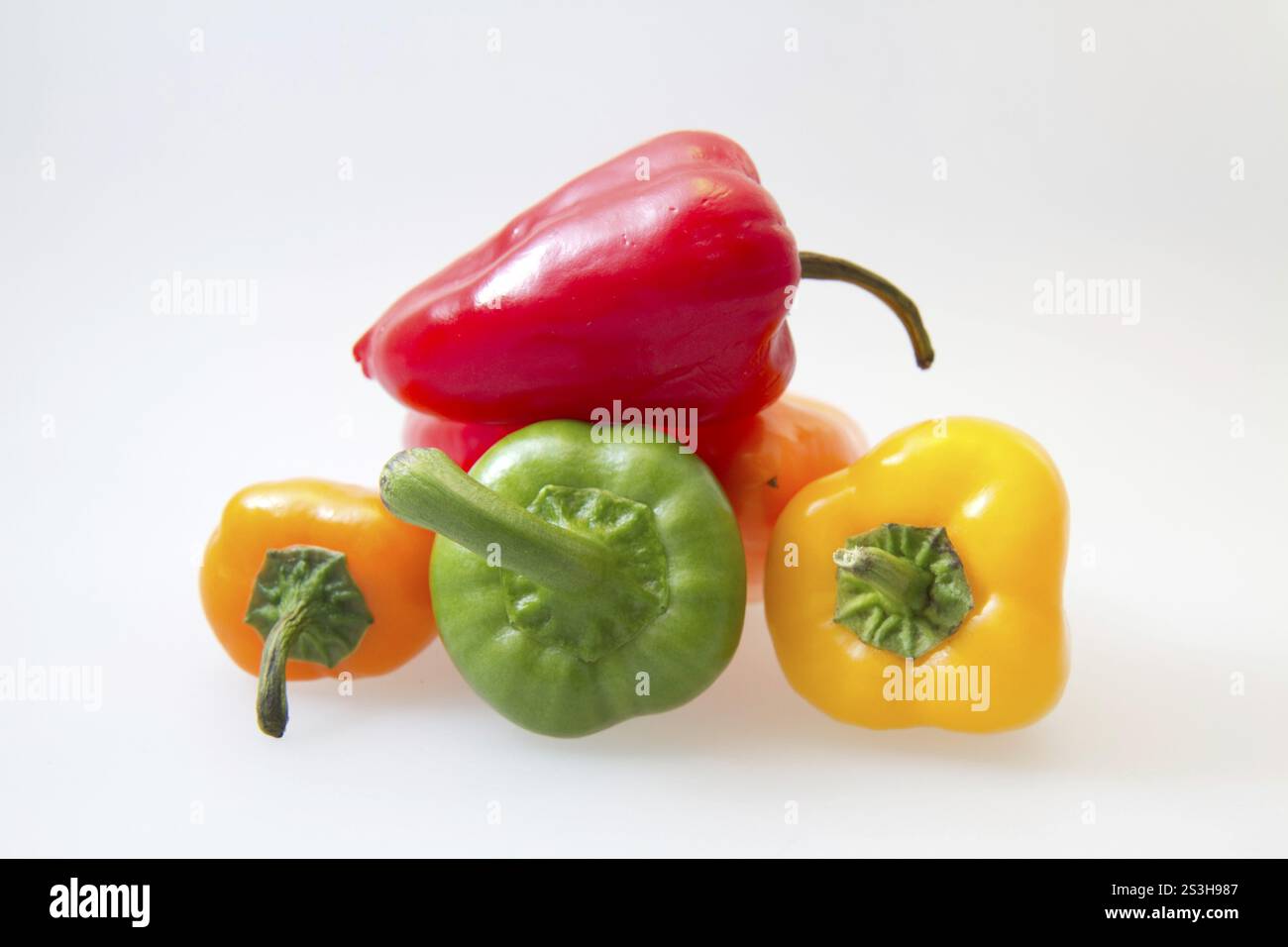 Red, green and yellow peppers on a white background Stock Photo - Alamy