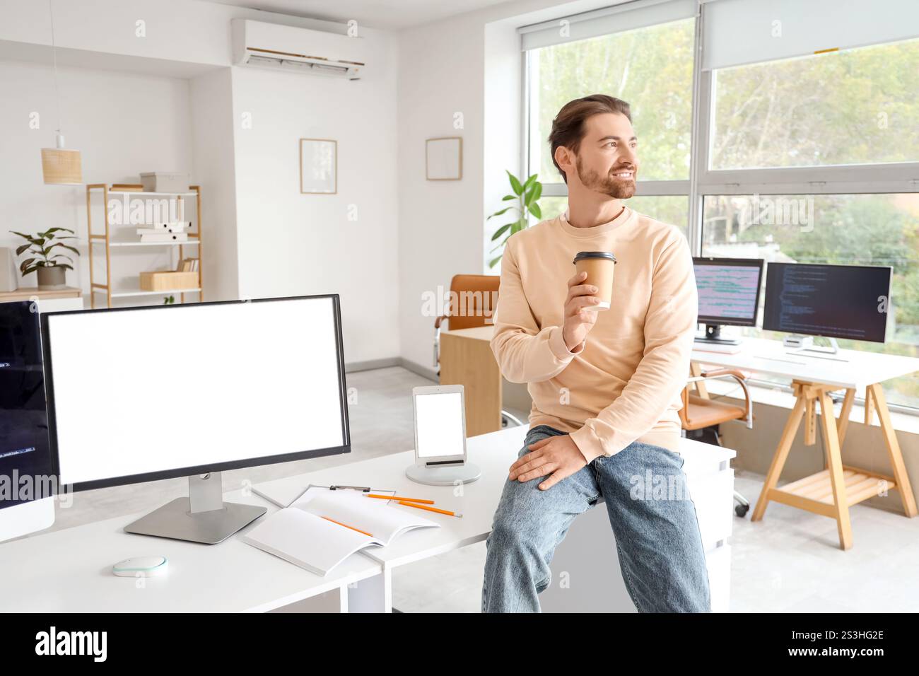 Male programmer drinking coffee in office Stock Photo