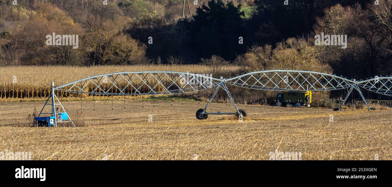An agricultural irrigation system is actively watering crops in a rural area, showcasing the essential technology used to support farming. Surrounding Stock Photo