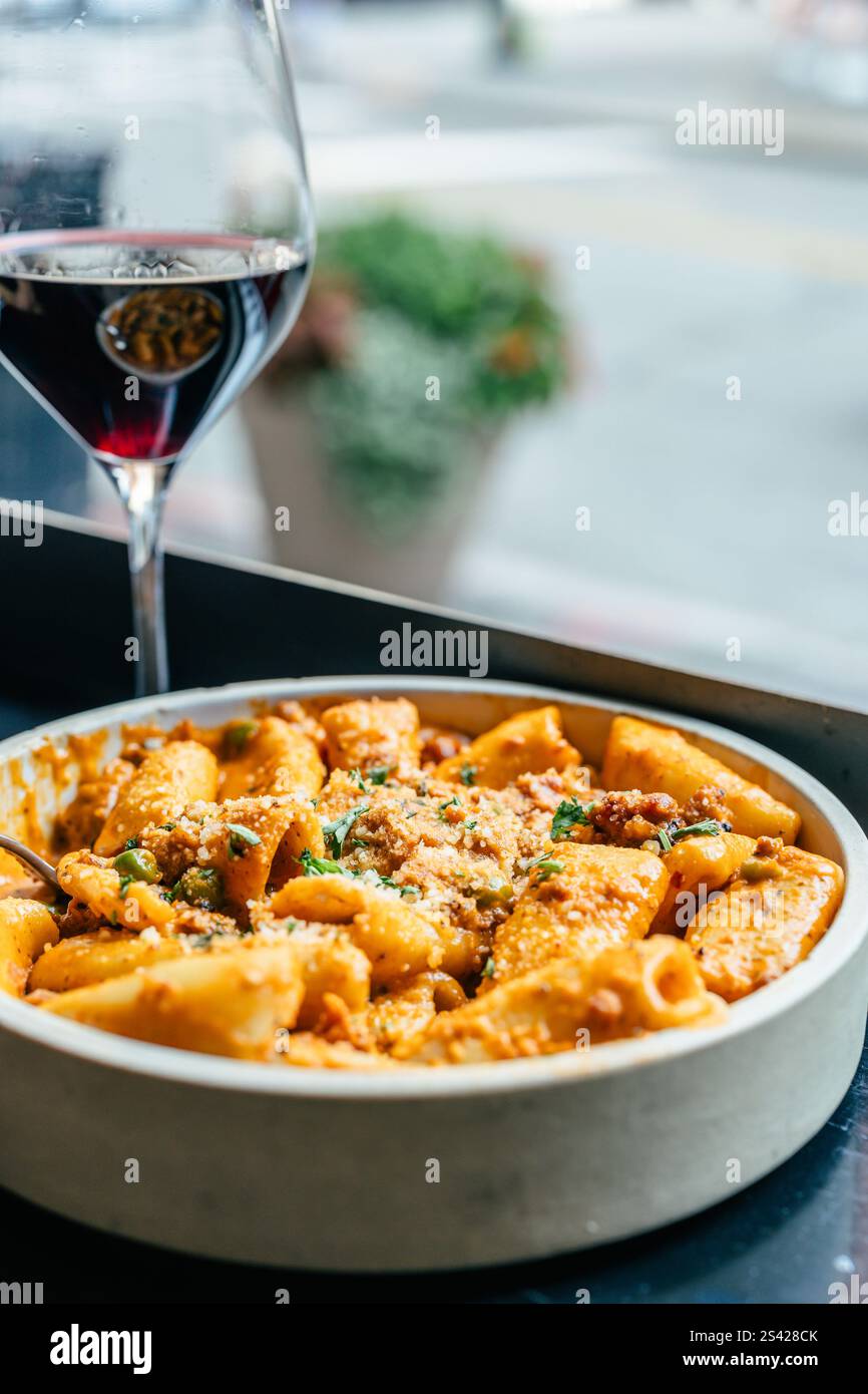 Pasta with red sauce served with a glass of red wine by the window. Stock Photo