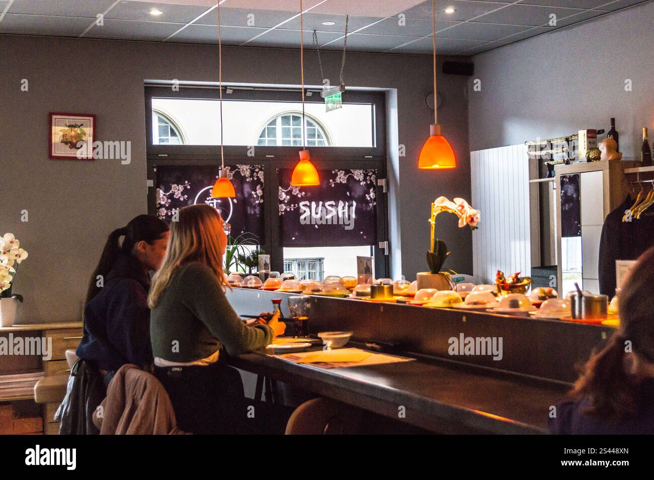 Rwo young women seated at a conveyor belt of dishes at Fuji Sushi Bar Trier, Rheinland-Pfalz, Germany Stock Photo
