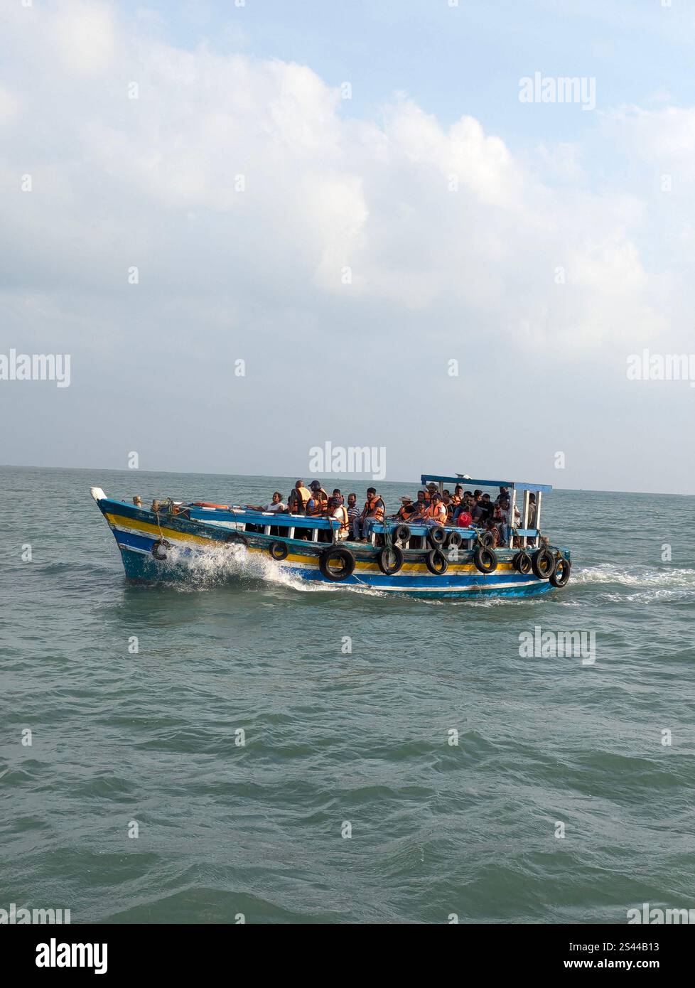 A boat heads to Delft Island, crossing calm seas under a cloudy sky, with passengers enjoying the journey. - Smartphone Captured Stock Image