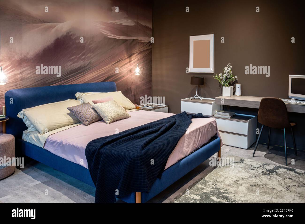 Comfortable and modern bedroom interior featuring a blue bed and a functional workspace Stock Photo