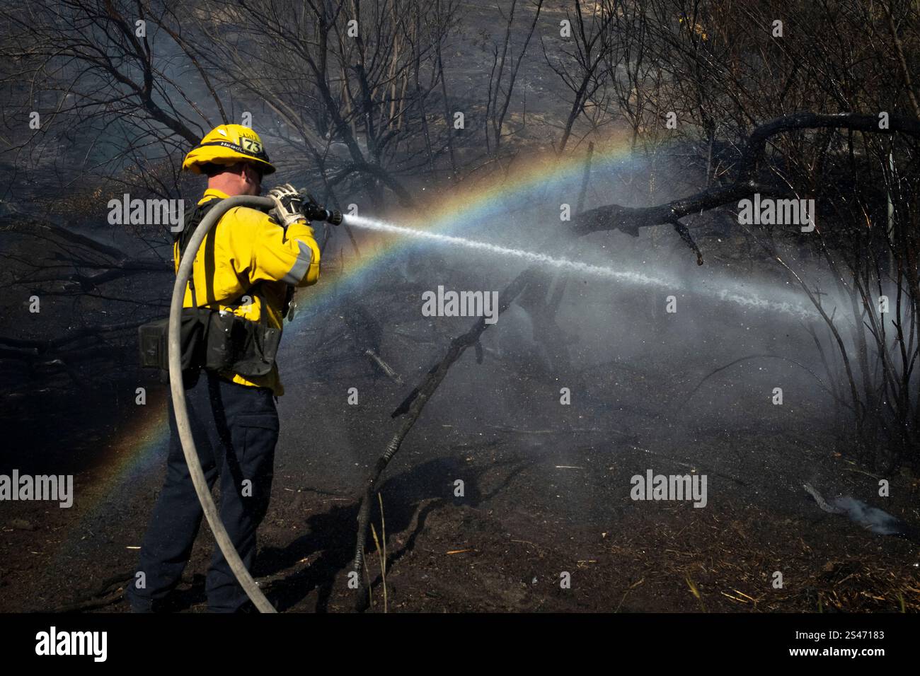 A firefighter hoses down hot spots from the Archer Fire in the Granada