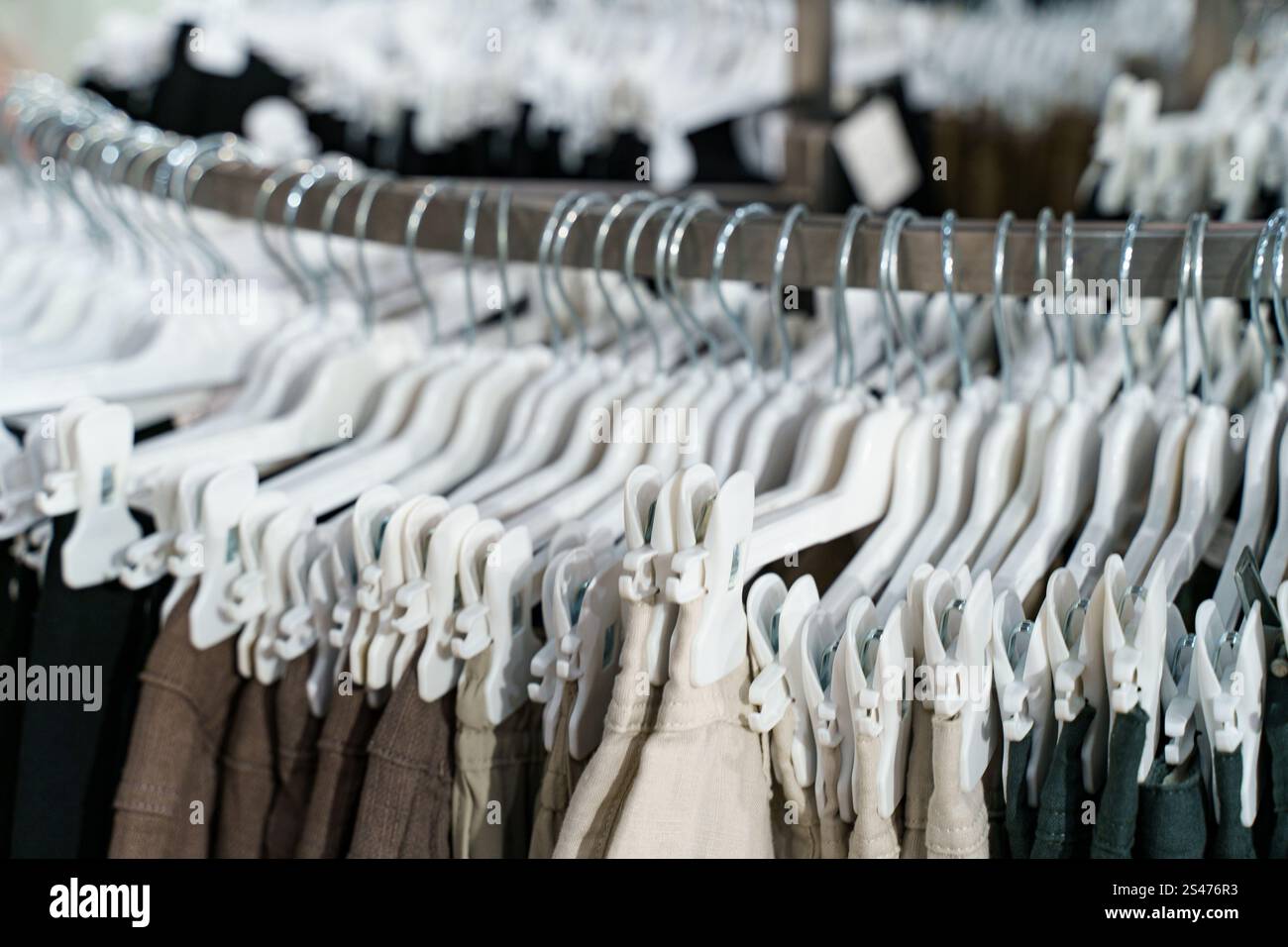Shoppers browse through orderly racks filled with an assortment of pants. The neutral colors create an inviting atmosphere. Stylish options cater to d Stock Photo