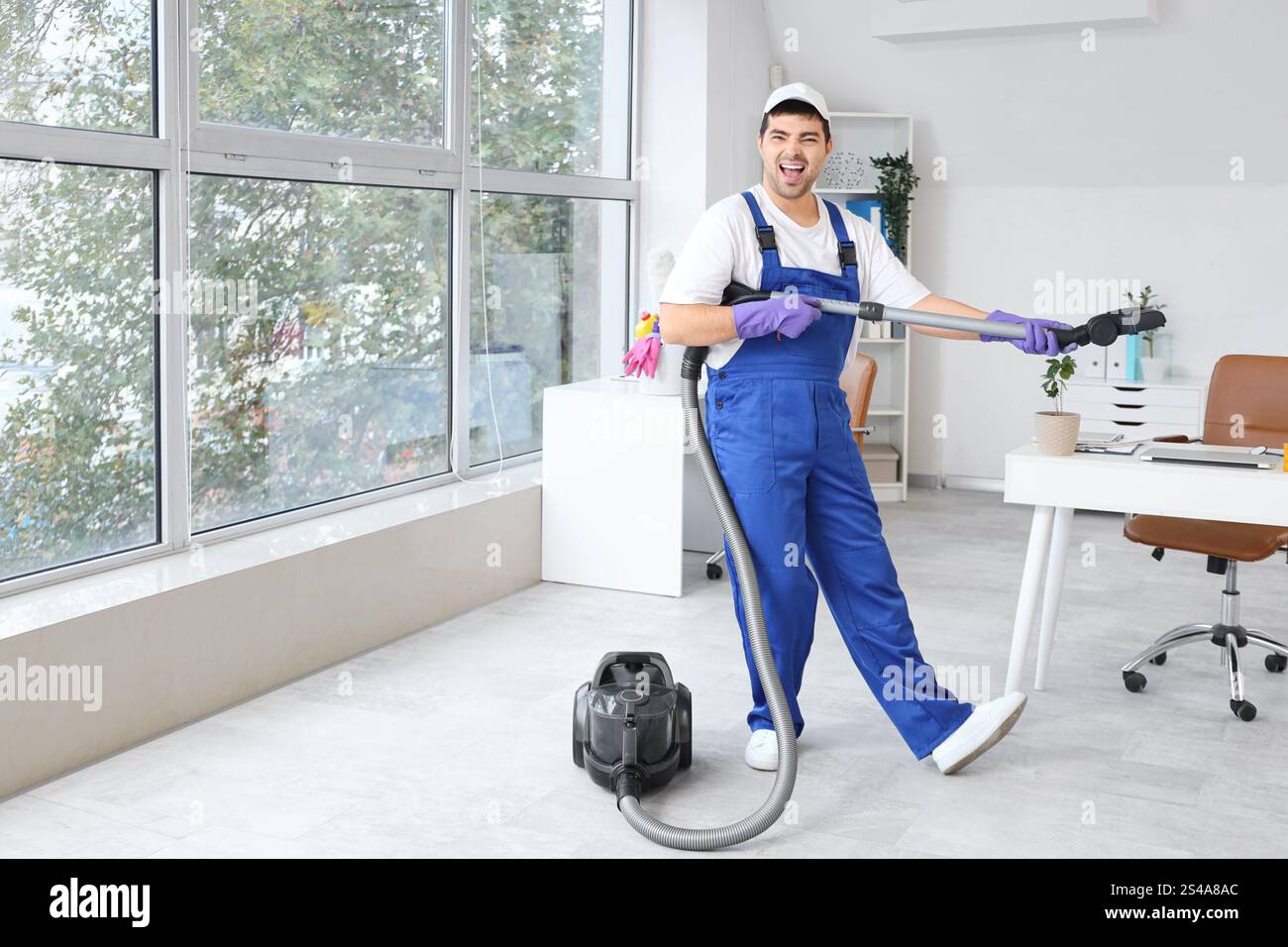 Janitor having fun while vacuuming floor in office Stock Photo