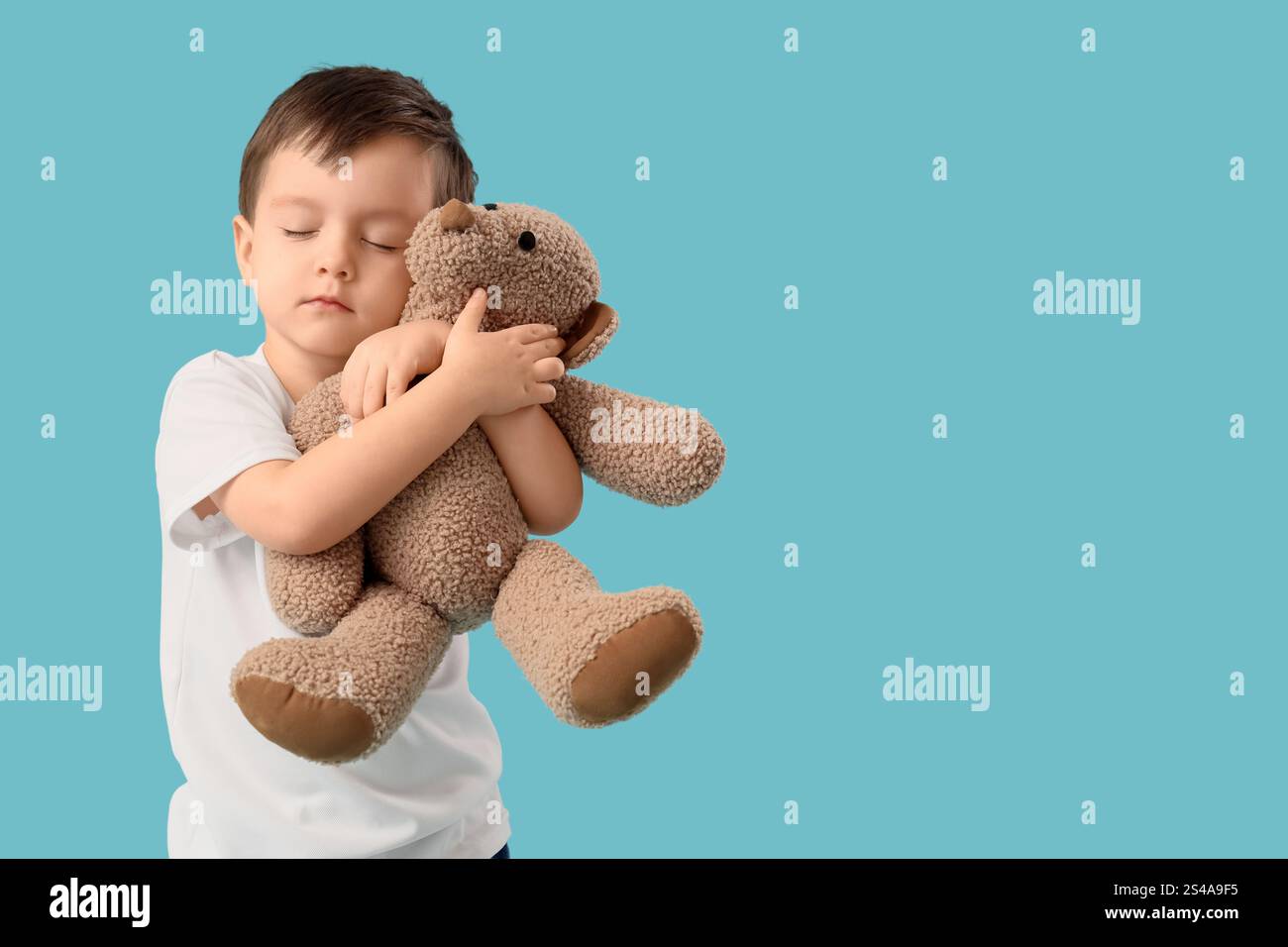 Cute little boy hugging toy bear on blue background Stock Photo - Alamy