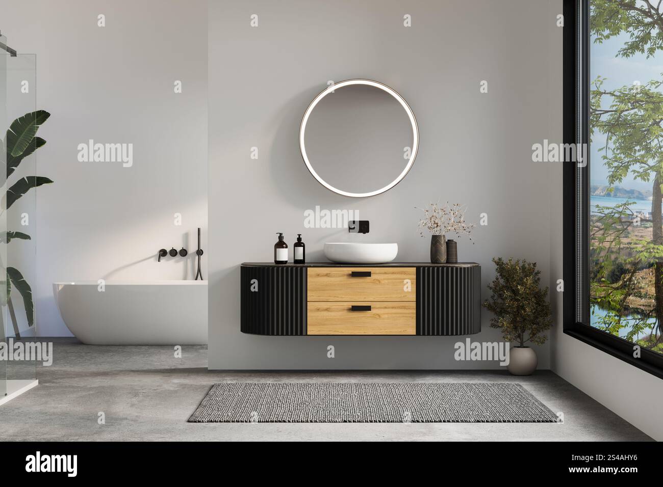 View of Modern bathroom with wood and black vanity, illuminated round mirror ...