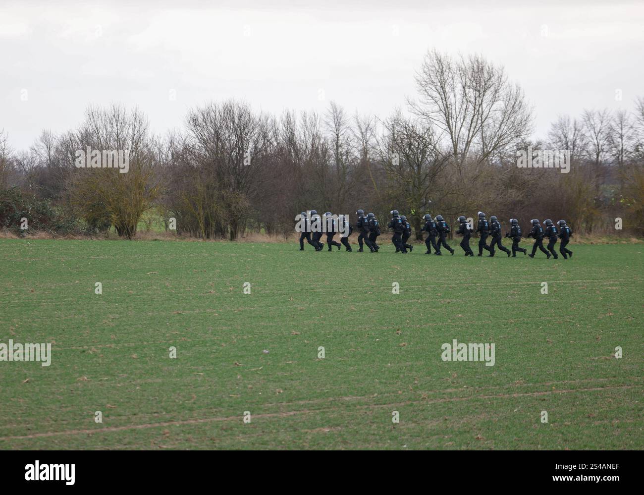 Riesa, Germany. 11th Jan, 2025. Police officers run across a field to ...