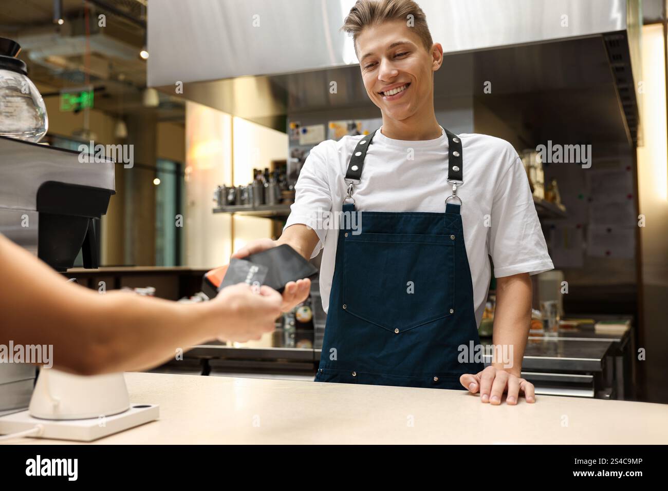 Cafe worker taking payment from client via terminal indoors Stock Photo ...