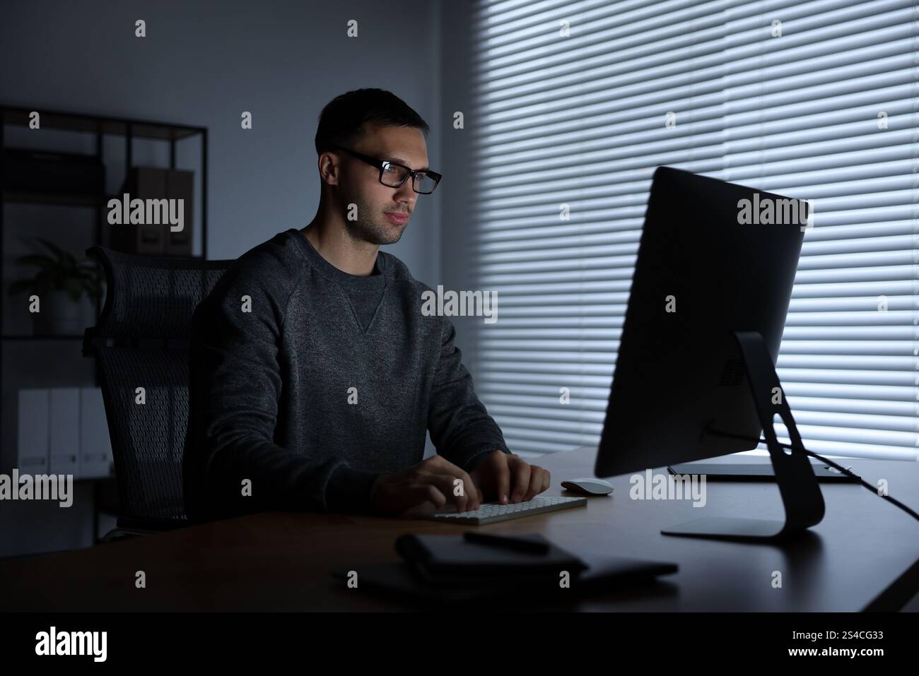 Programmer working on computer indoors at night Stock Photo