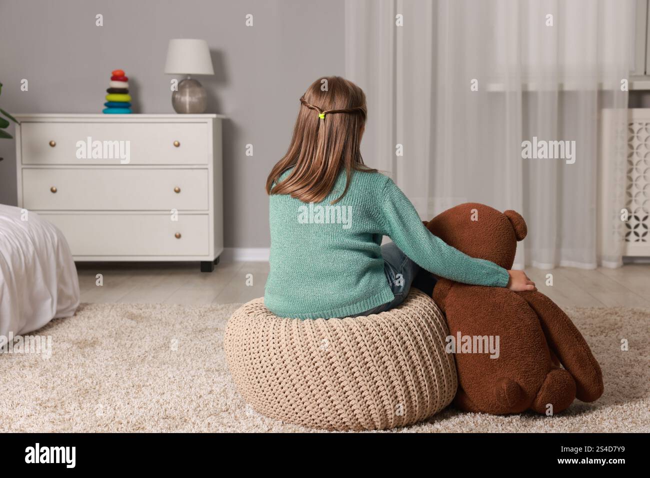 Autism concept. Lonely little girl with teddy bear at home, back view ...