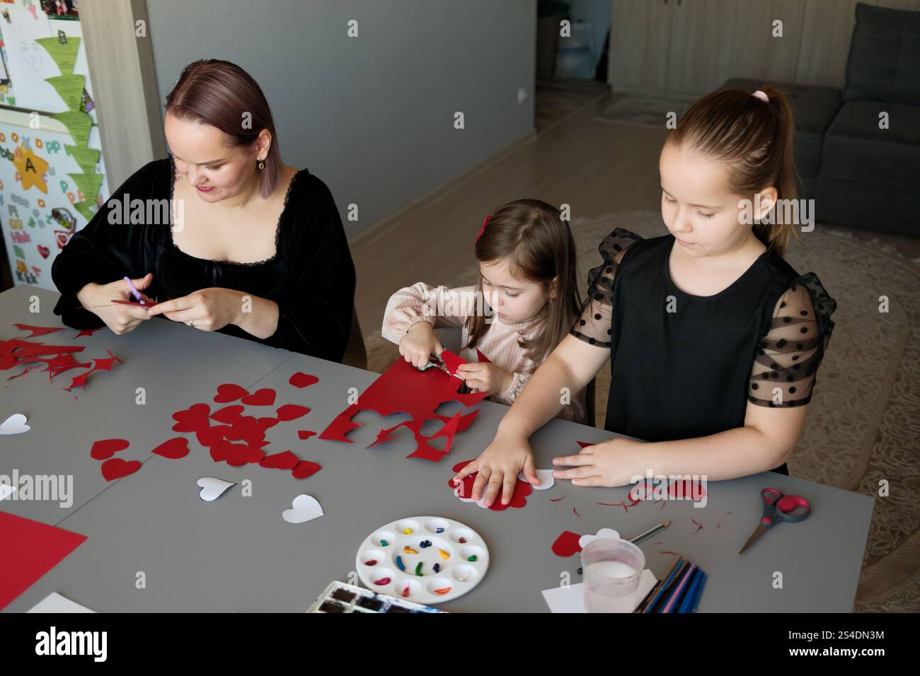 Family crafting session together with red and white paper art projects ...