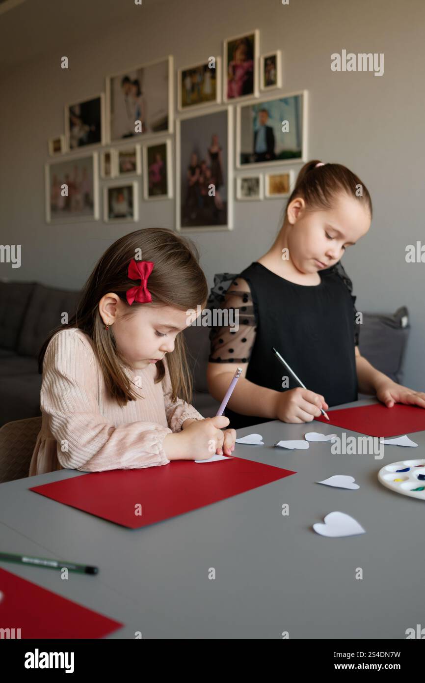 Two Girls Engaged in Crafting Activities at a Desk With Red Cardstock ...