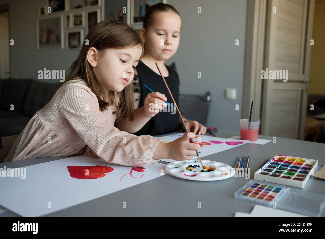Two young girls painting together at home with watercolor paints Stock ...