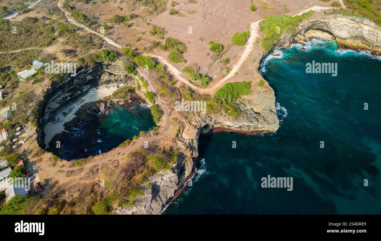 Drone shot of a natural bridge connecting a collapsed cave to a ...
