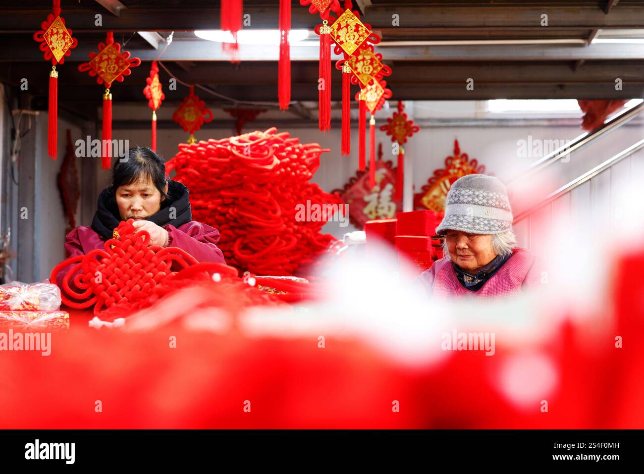 SUQIAN, CHINA - JANUARY 12, 2025 - A worker produces a true love knot ...
