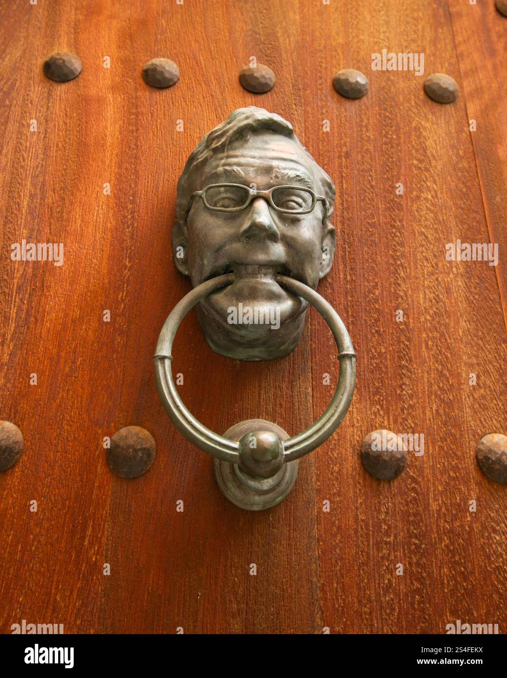 Knob of an old wooden door with a man's face carved in iron. Stock Photo
