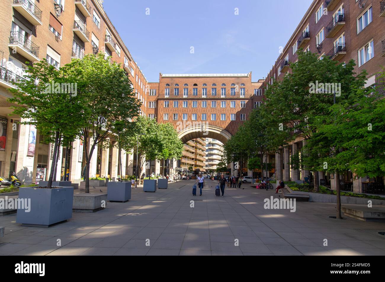 Modern pedestrian street with green trees, benches, and an iconic ...