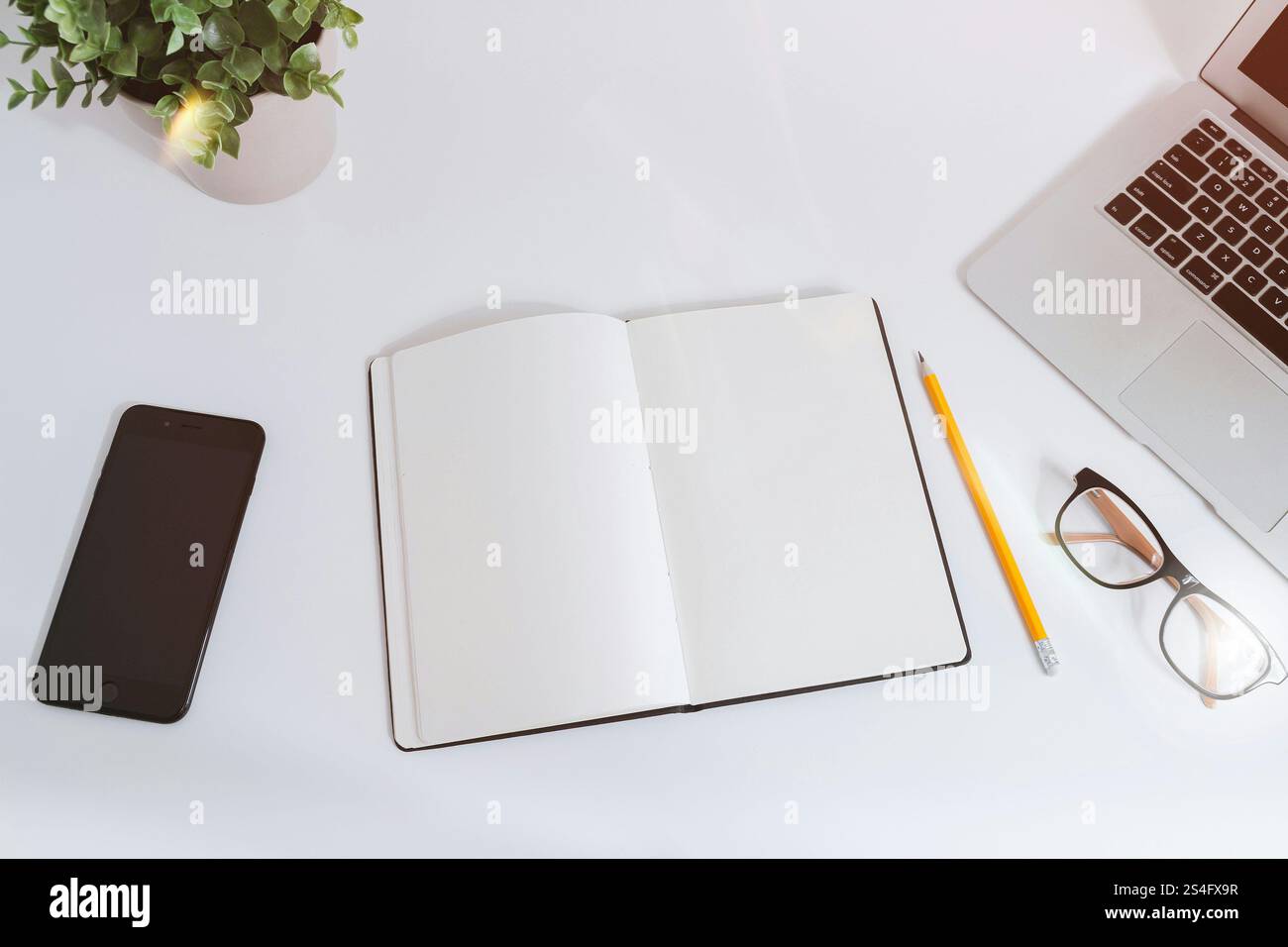 An open empty notebook on a white desk next to a computer Stock Photo