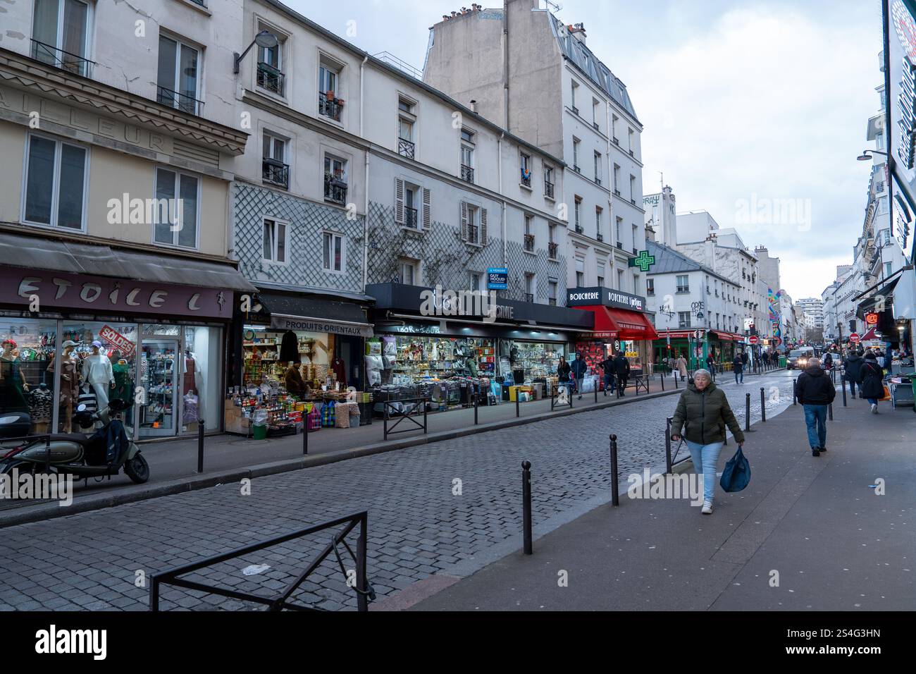 Busy street in Paris with shops and pedestrians on an overcast day Stock Photo