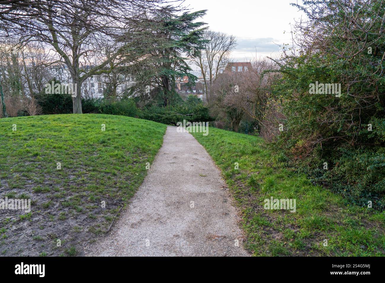 Pathway through a scenic green park with trees and a gentle slope Stock ...