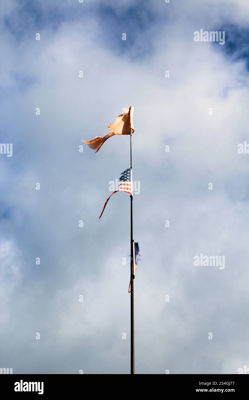 Zwei, einem Masten befestigte, Flaggen: Beide Flaggen sind zerfetzt. Die untere Flagge ist die amerikanische Nationalflagge 'Stars and Stripes'. Stock Photo