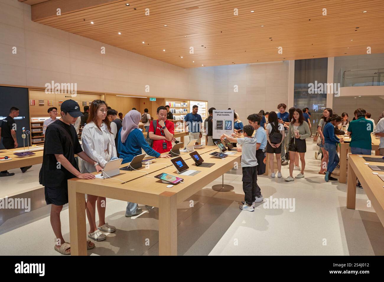 People look at selection of iPads in the Apple Store inside the Exchange TRX shopping mall. Kuala Lumpur, Malaysia. Stock Photo