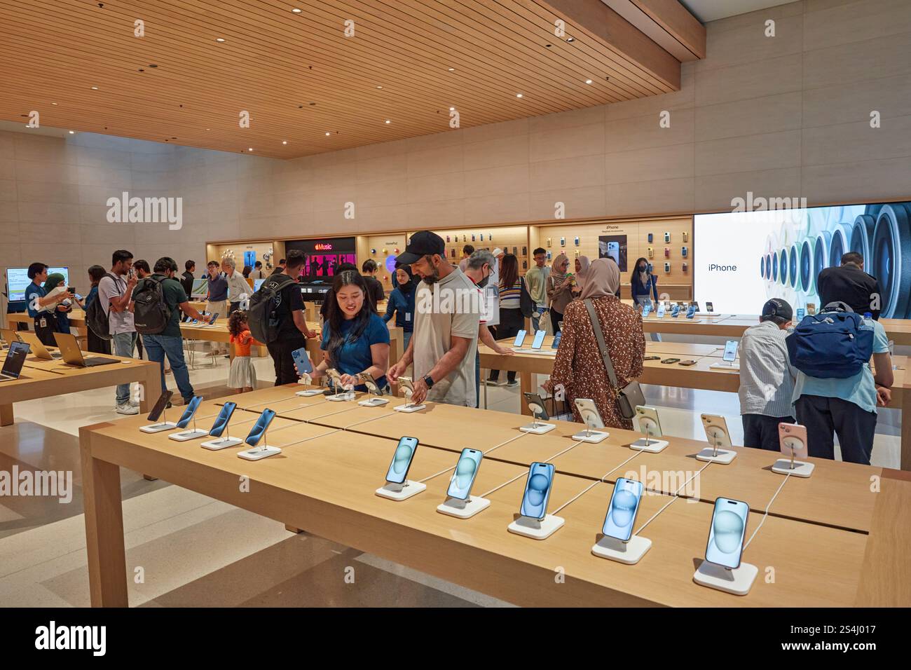 People look at selection of iPhones in the Apple Store inside the Exchange TRX shopping mall. Kuala Lumpur, Malaysia. Stock Photo