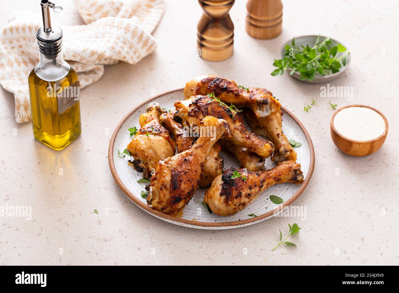 Appetizing roasted or grilled chicken legs garnished with herbs, served on a kitchen table Stock Photo