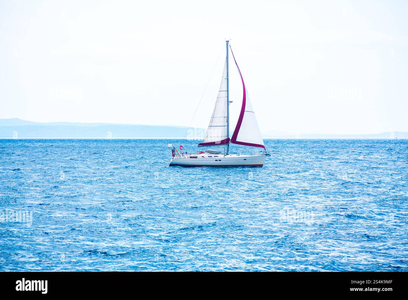 Sailboat gliding across the calm ocean waters under a clear blue sky ...