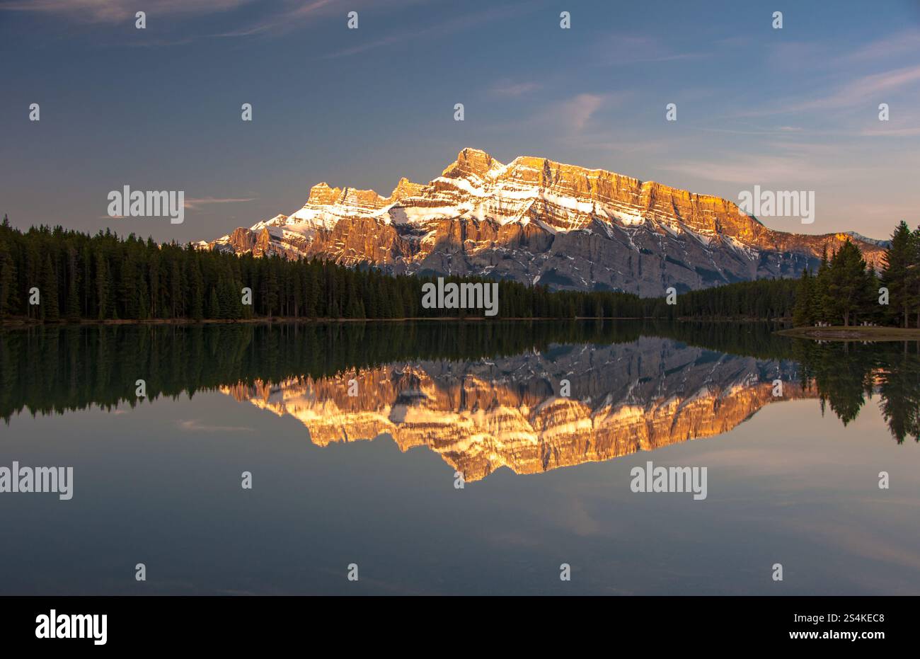Sunrise light illuminates Rundle Mountains which reflects off Two Jack ...
