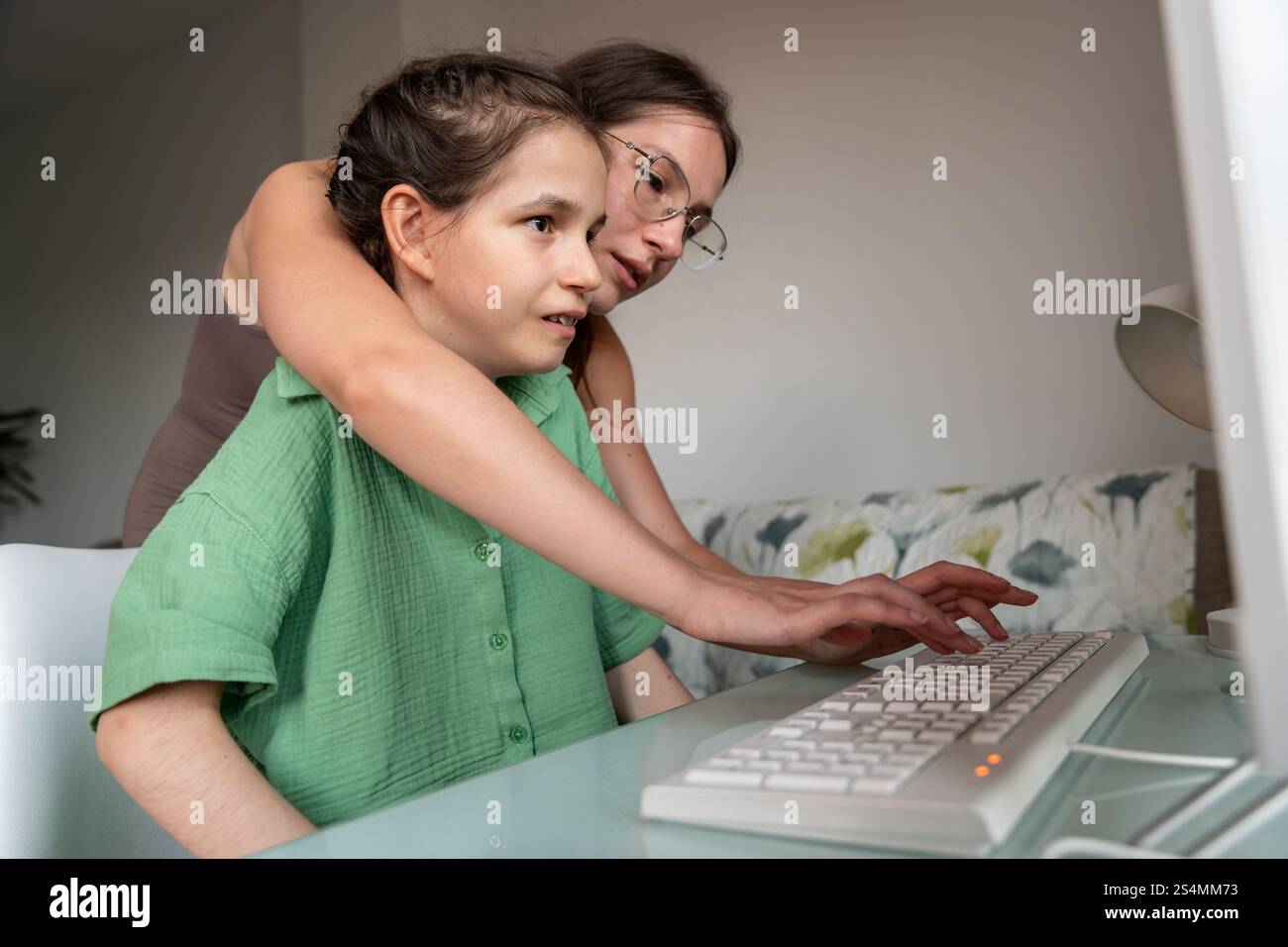 A sister shares a moment as she helps a girl with a tracheostomy use a ...