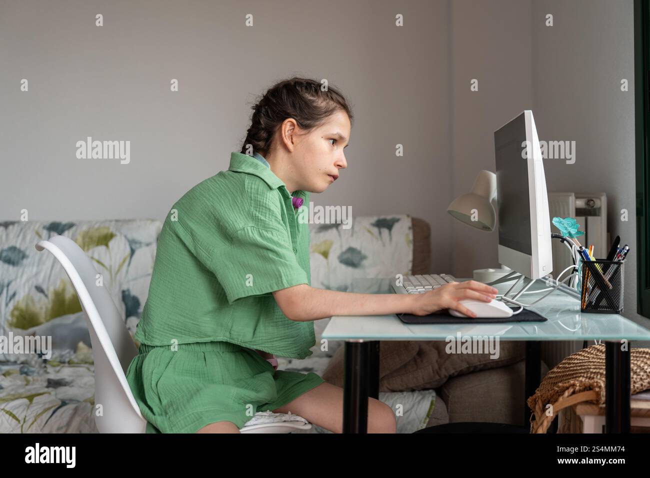 A young girl with a tracheostomy sits at a desk, engaged with a ...