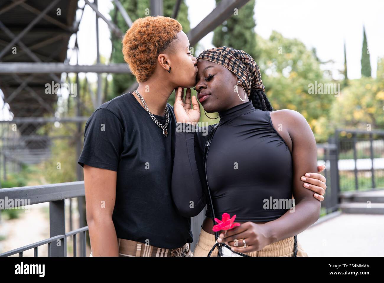 A loving LGBTQ multiethnic couple embraces in a park, sharing a tender ...