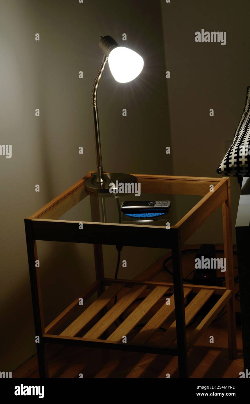 A bedside lamp and a phone on a little table Stock Photo