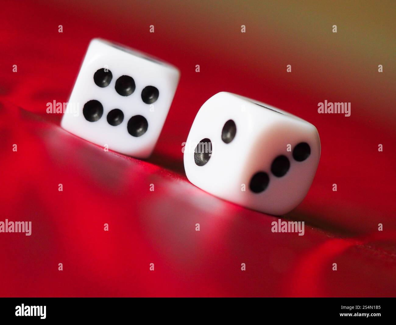 Two white plastic dice on a red table Stock Photo