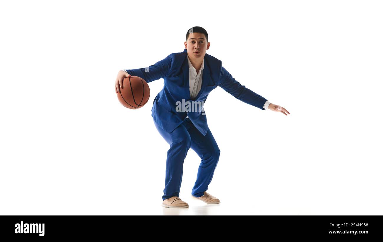 Man in blue suit balancing basketball in defensive sports posture ...