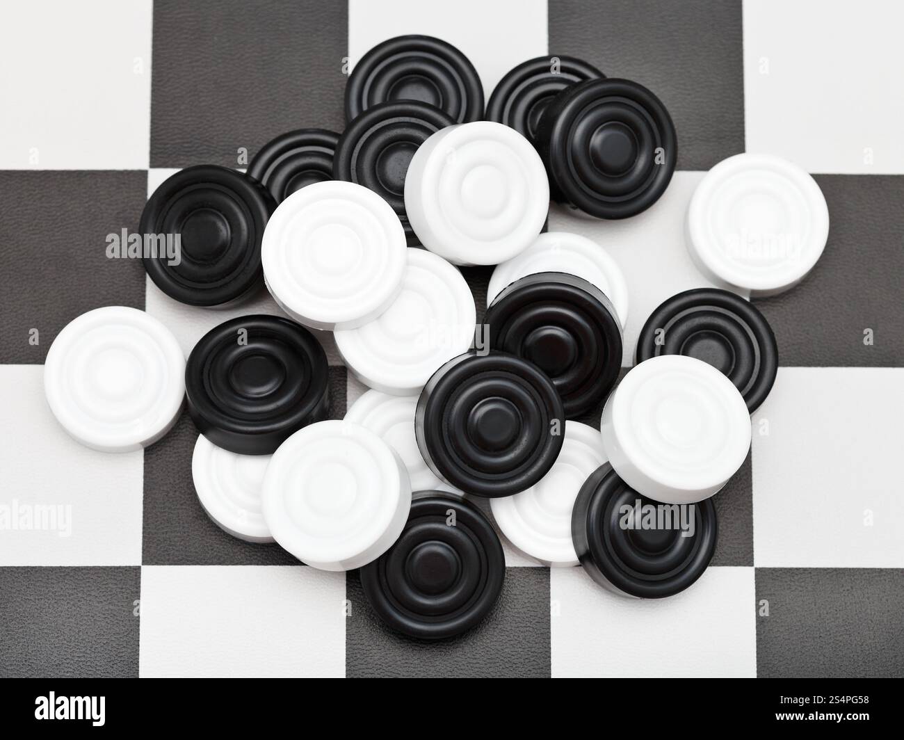 pile of draughts on black and white checkerboard Stock Photo