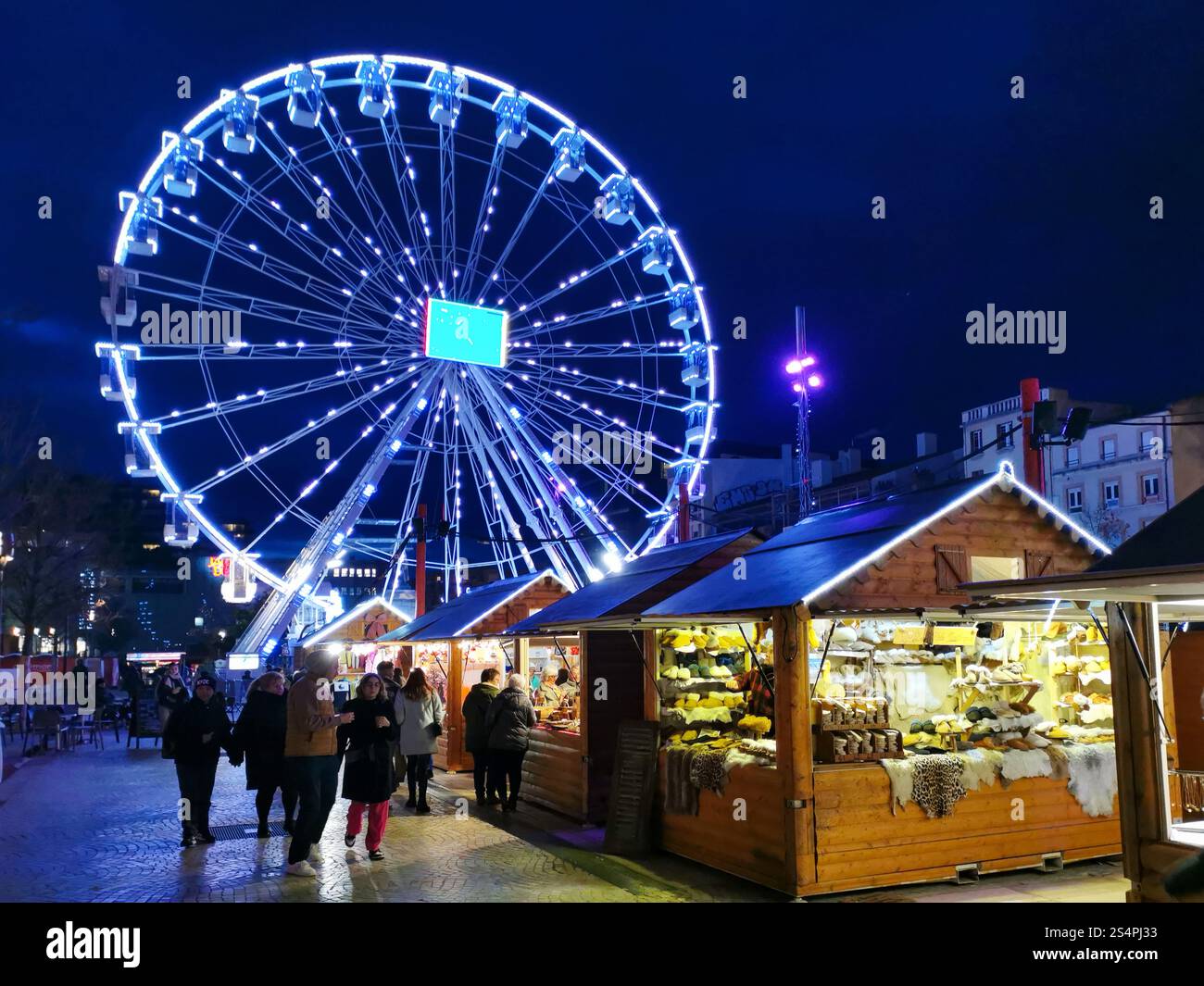 Visitors enjoy a festive atmosphere at the Christmas market on Place de Jaude, Clermont-Ferrand, featuring charming wooden stalls and a brightly lit F - Smartphone Captured Stock Image